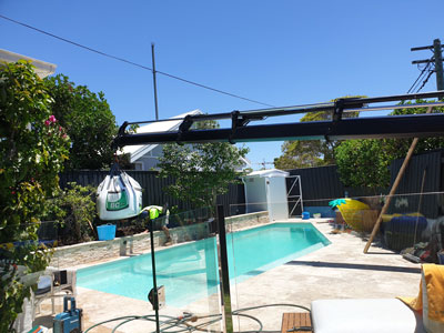 Crane truck lifting under wires and over pool