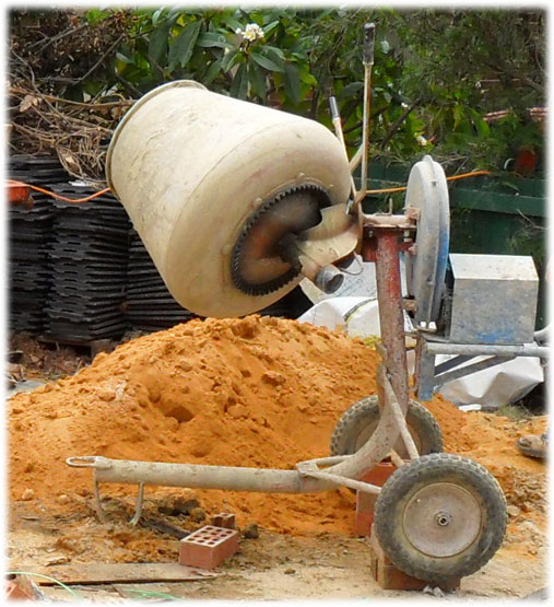 Brickies sand in a pile next to a cement mixer
