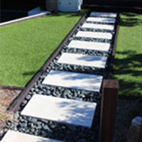 White pavers contrast with black polished pebbles